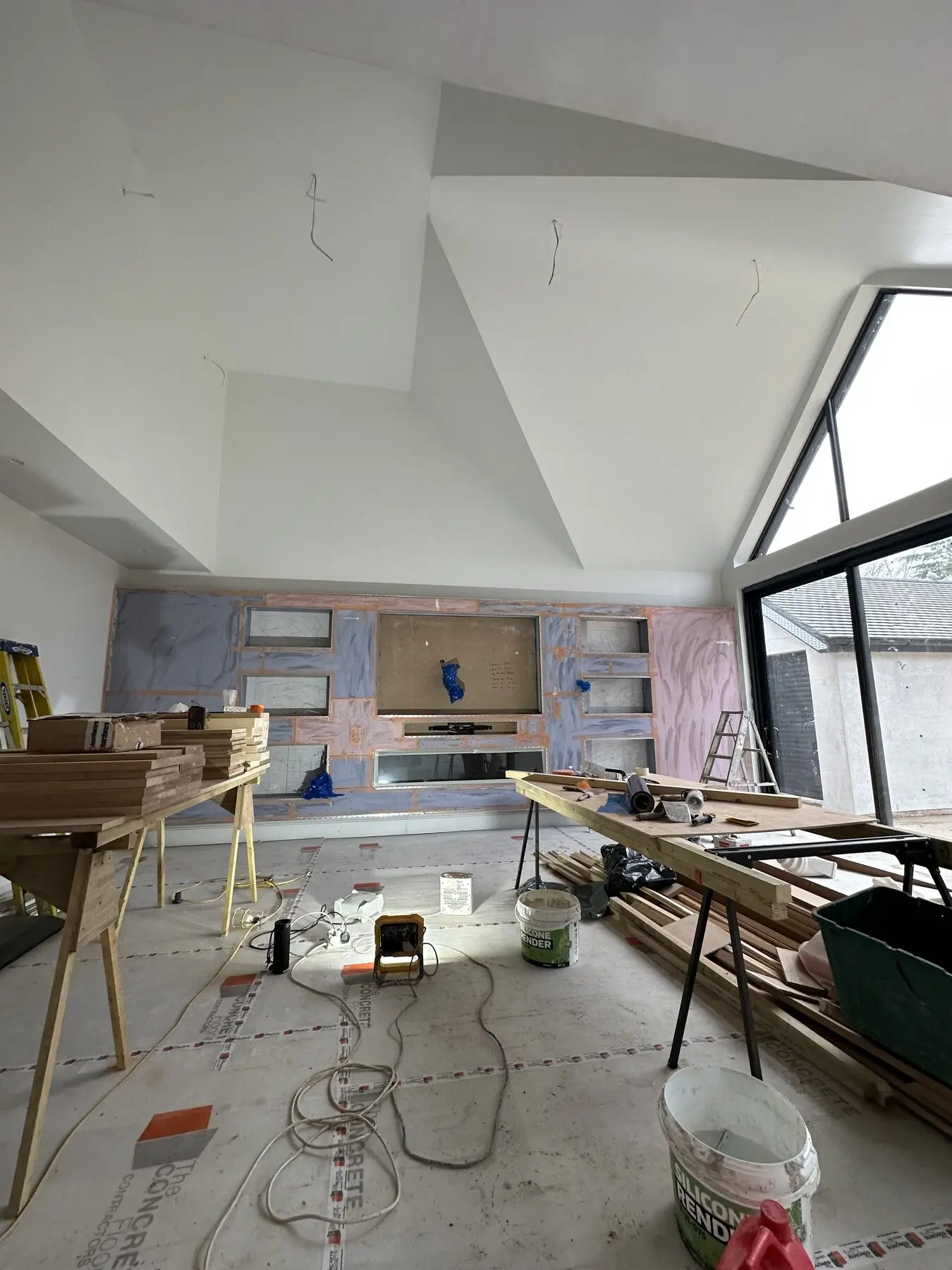 House skim work in progress in London with timber tables and broad fresh plastering across walls